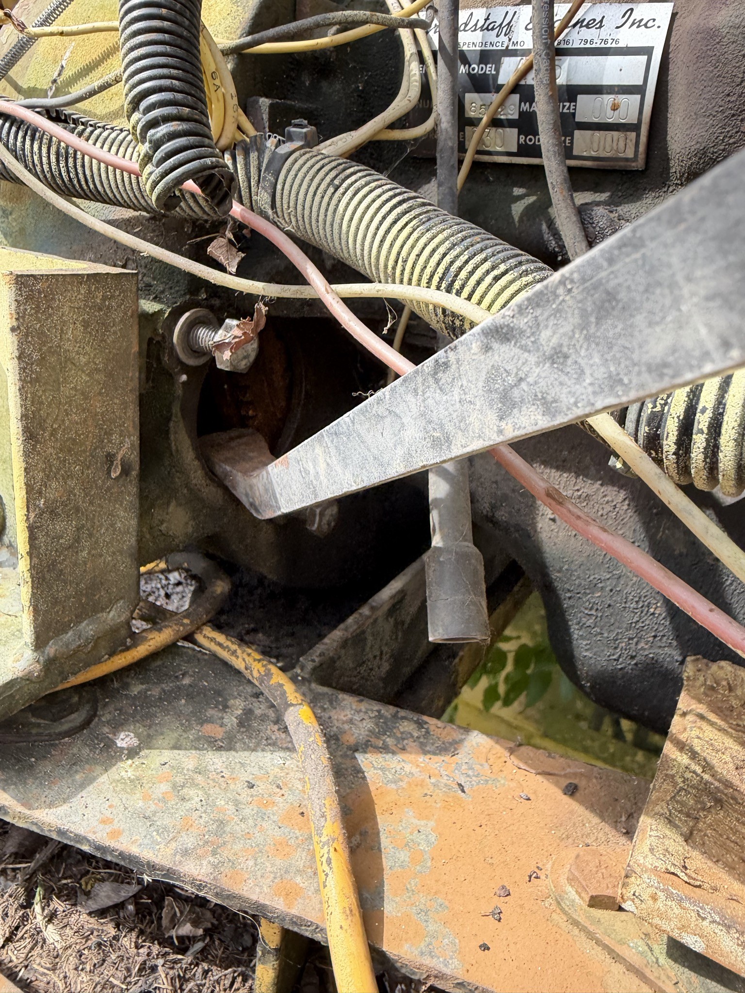 Flywheel ring gear visible through the empty starter opening, pry bar engaged against the teeth