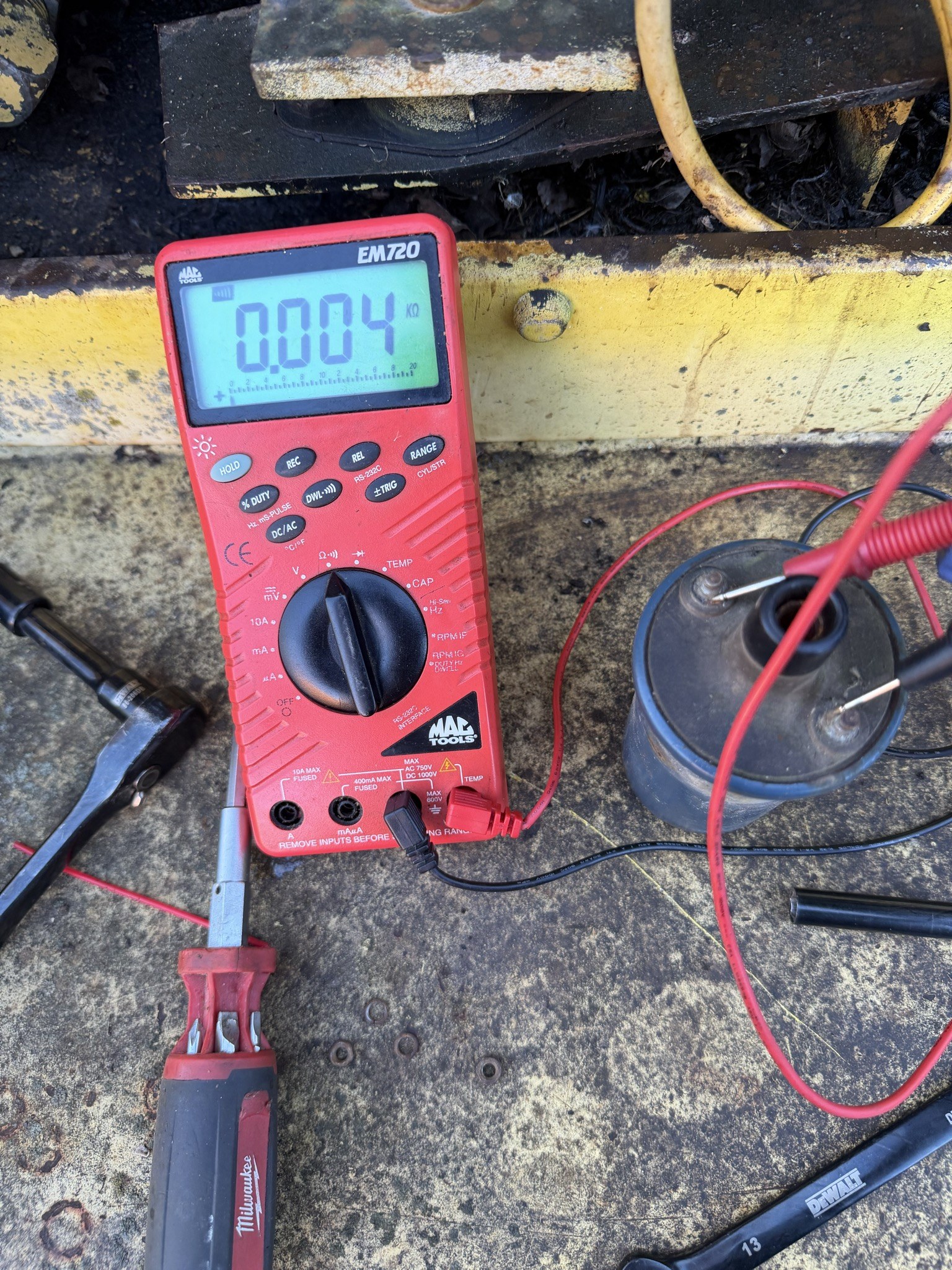 Meter reading 0.004 kilohms with both probes on the coil’s low-tension terminals