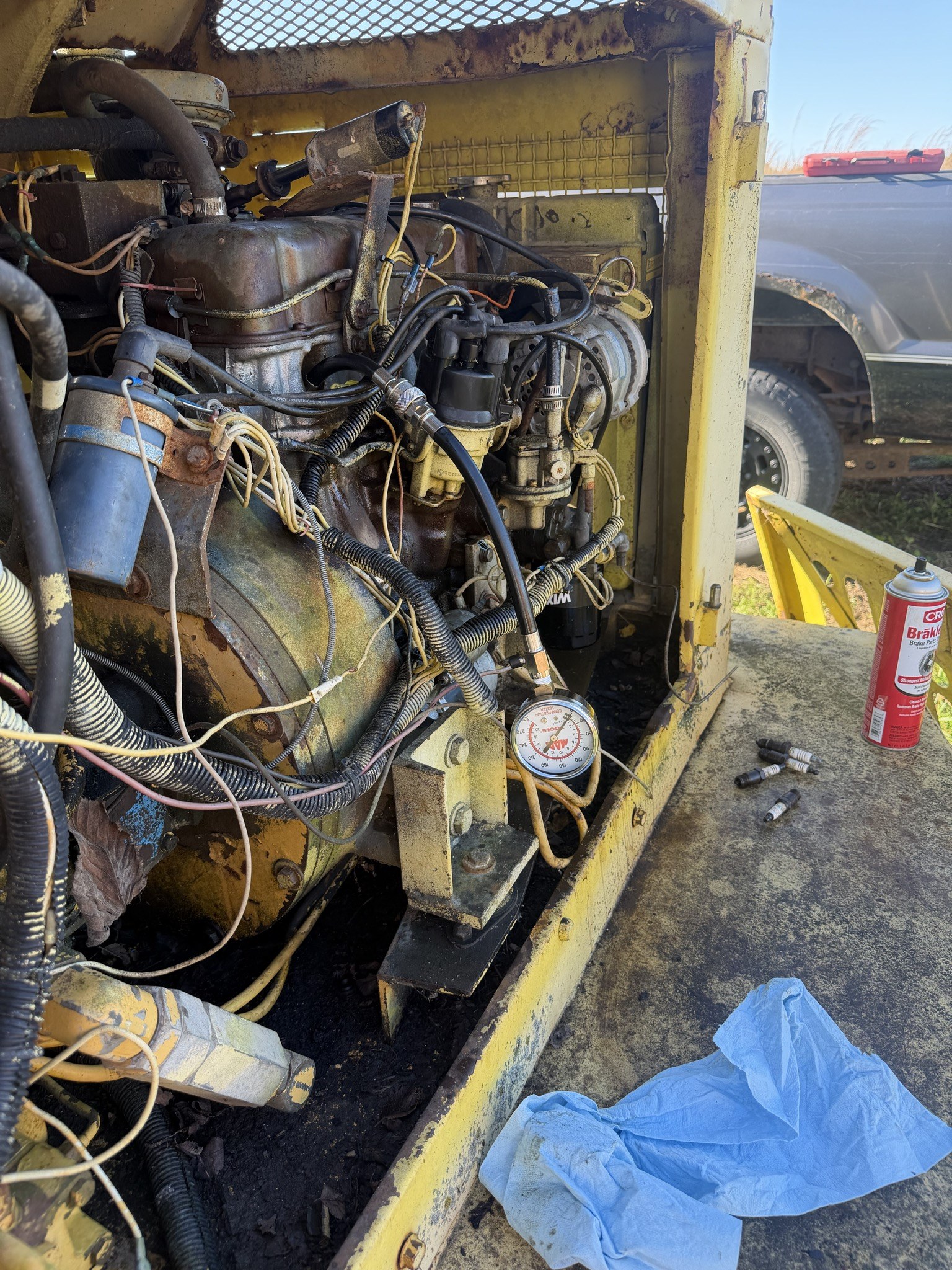 Engine bay open on the machine, plugs and brake cleaner laid out on the deck