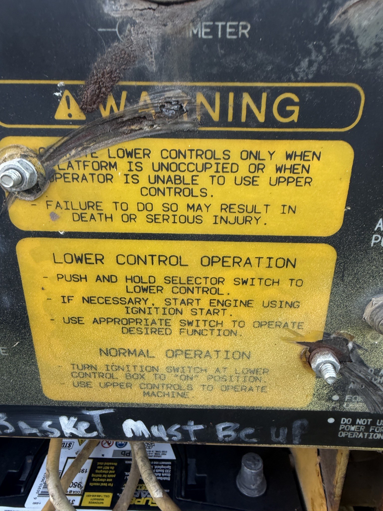 Warning placard on the ground controls describing lower control operation